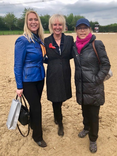 Three beautiful blonde women standing in a sand arena